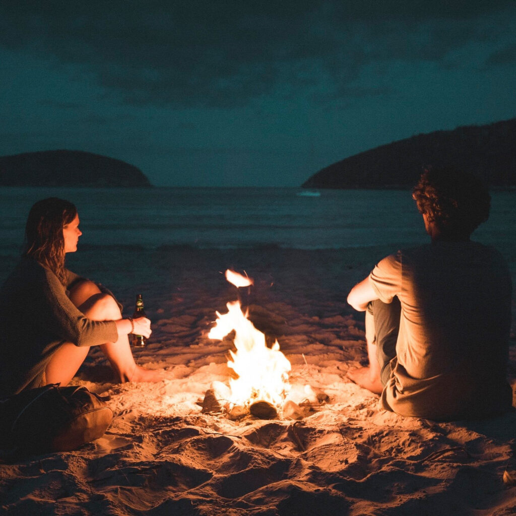 Couple sitting on a beach lit by campfire