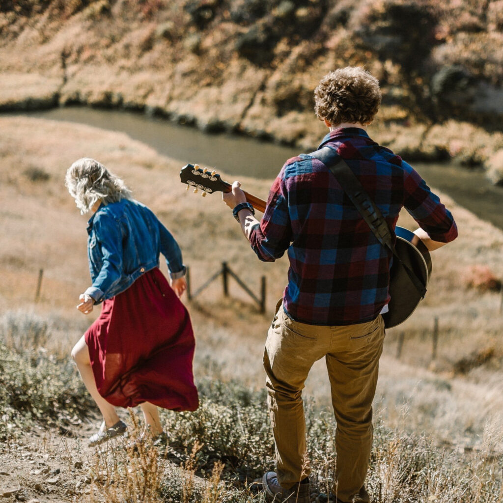 Couple in field playing a guitar