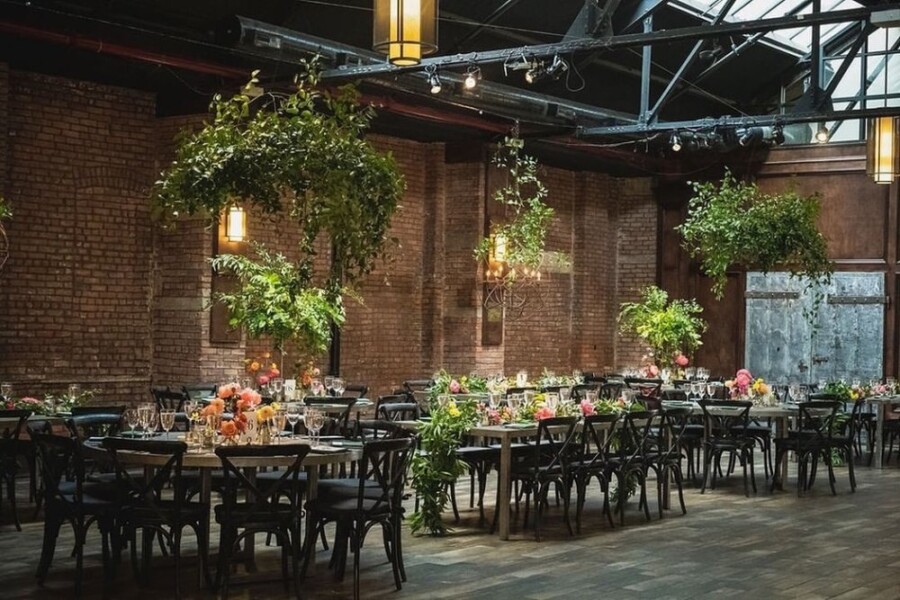 Industrial style wedding reception room with round tables decorated with plants and flowers