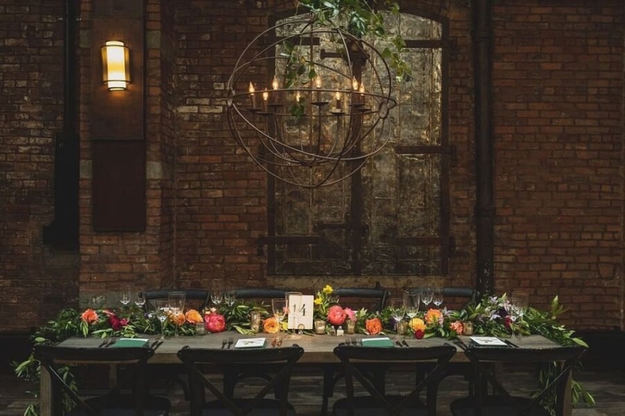 Wedding table decorated with flowers under large metal chandelier