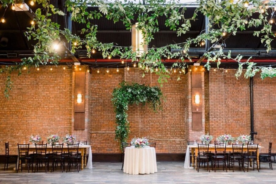 Industrial wedding reception hall decorated with tables, flowers and candles