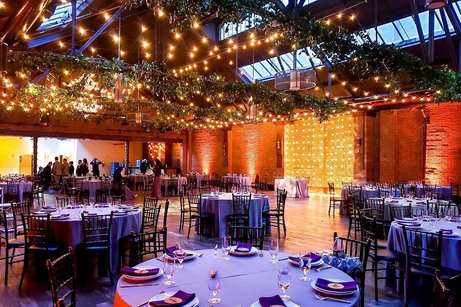 Wedding reception hall decorated with lights and flowers with round tables