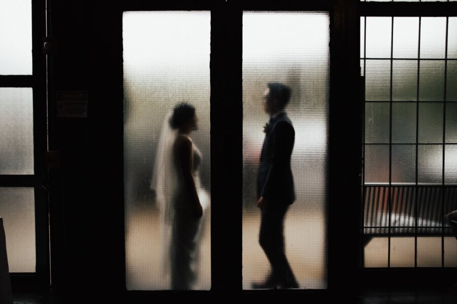 Bride and Groom standing behind frosted glass door
