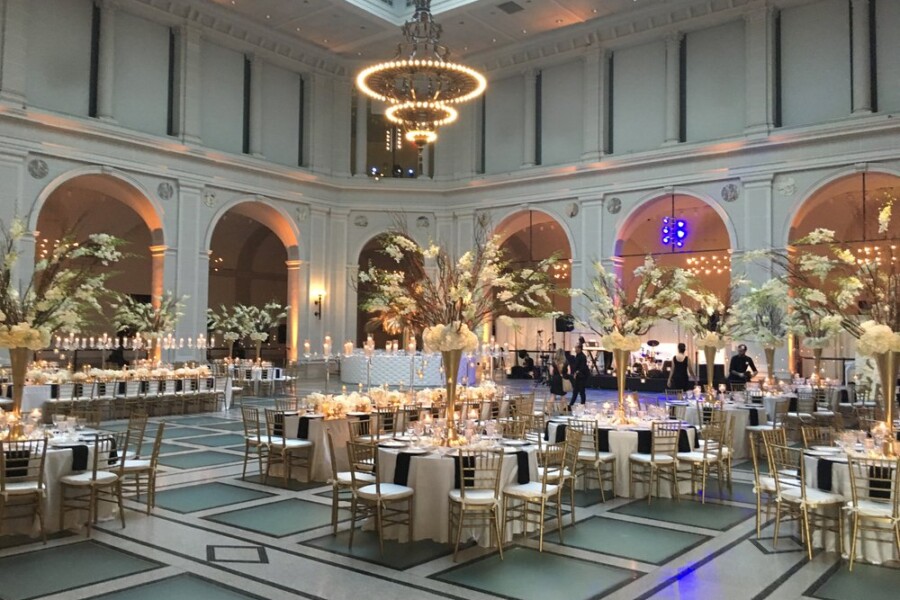 Wedding reception in large square room with round decorated tables and lights