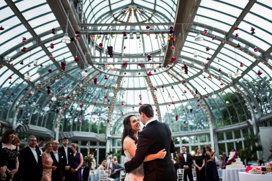 Bride and Groom embracing in front of guests in glass enclosed hall