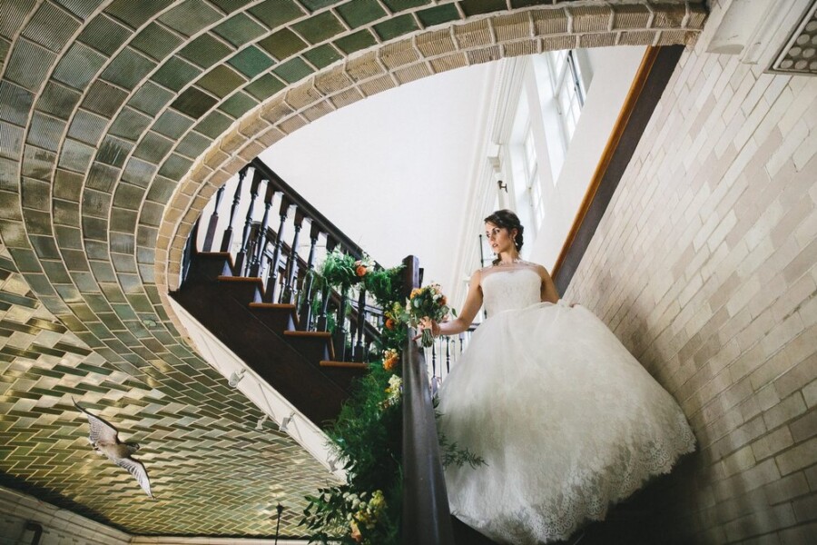 Bride holding bouquet walking down stairs